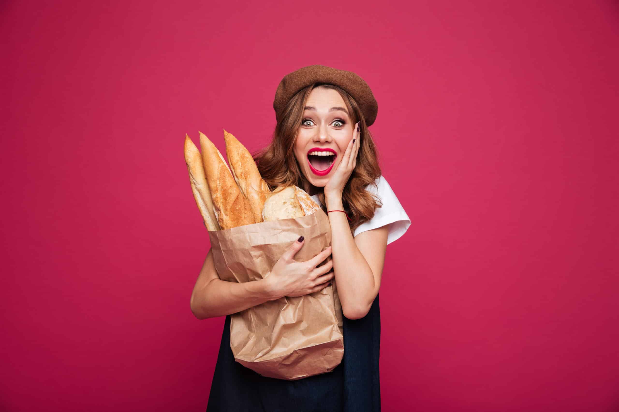 service-client Photo d'une femme souriante et heureuse tenant des baguettes de pain, illustrant la satisfaction client et le succès d'une expérience utilisateur réussie (UX) par Azuracom.