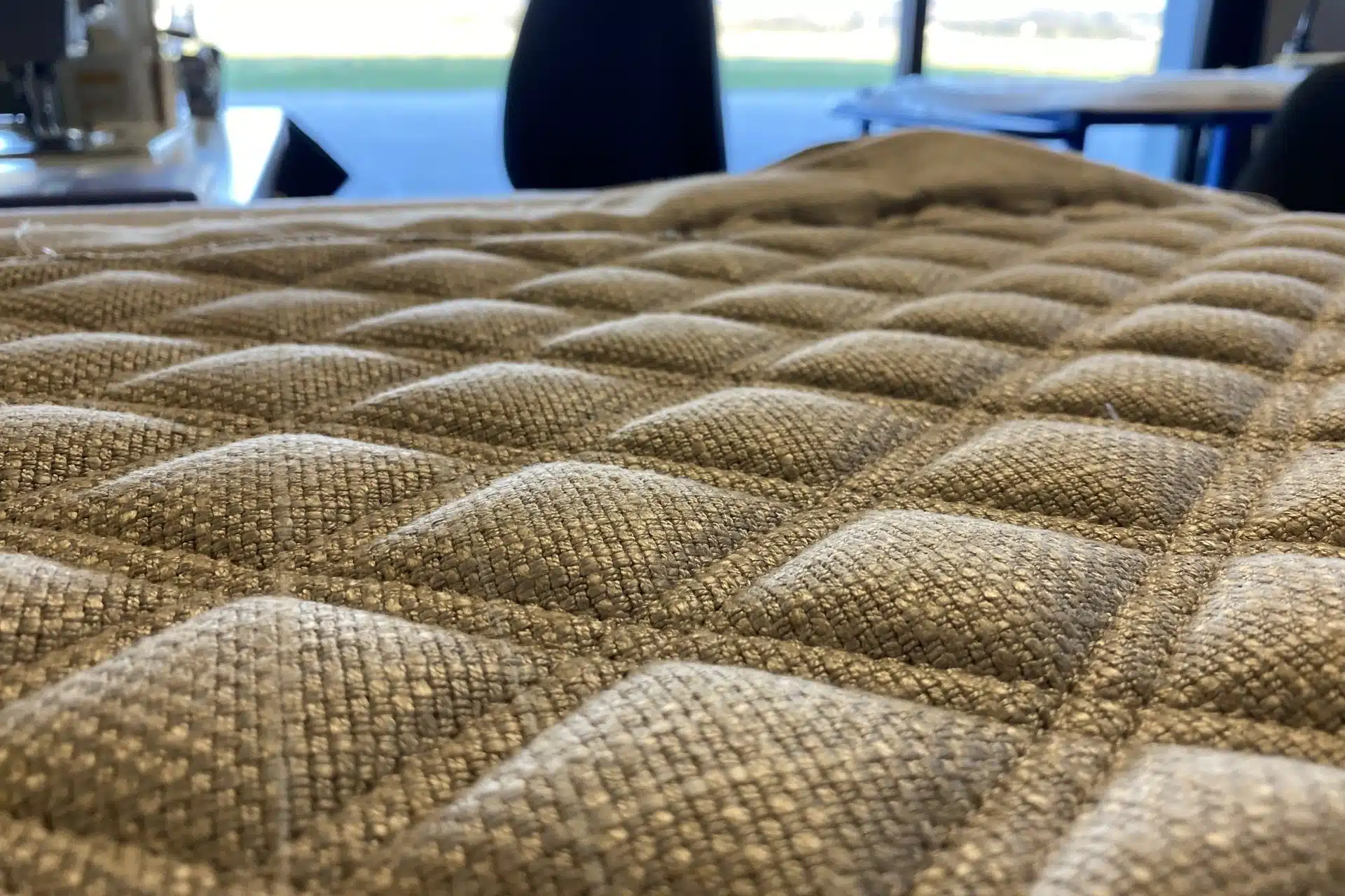 Gros plan sur un tissu matelassé haut de gamme, mettant en valeur la matière et les finitions d’un atelier présenté sur un site vitrine luxe.