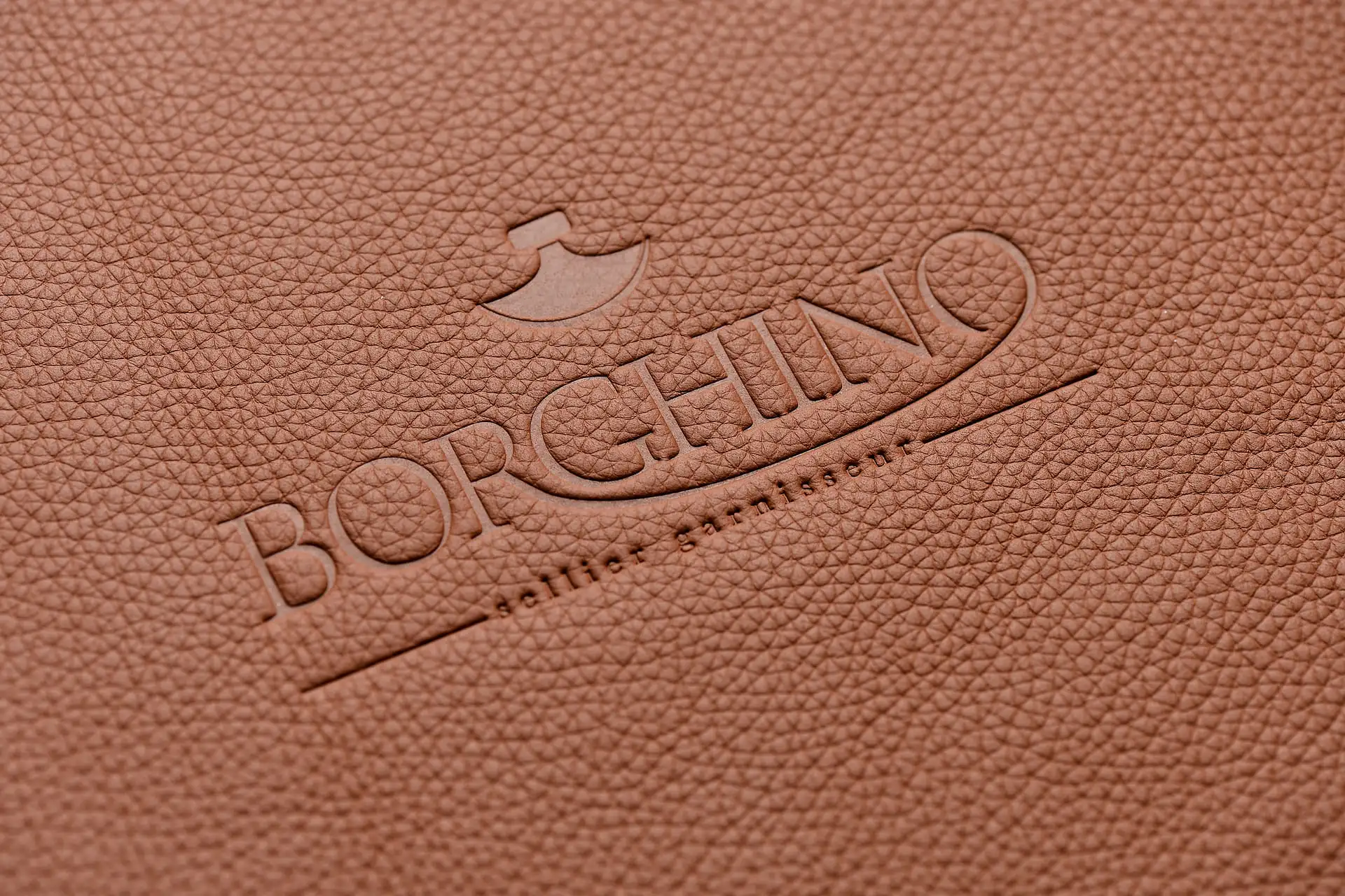Logo Borghino embossé sur un cuir texturé haut de gamme, illustrant l’élégance et le raffinement valorisés sur un site vitrine luxe.