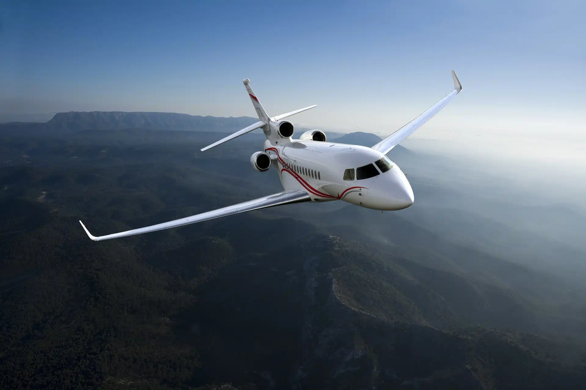 Avion Falcon 7X survolant une chaîne de montagnes, illustrant l’élégance et la qualité associées à un site vitrine luxe créé pour valoriser des aménagements intérieurs premium.