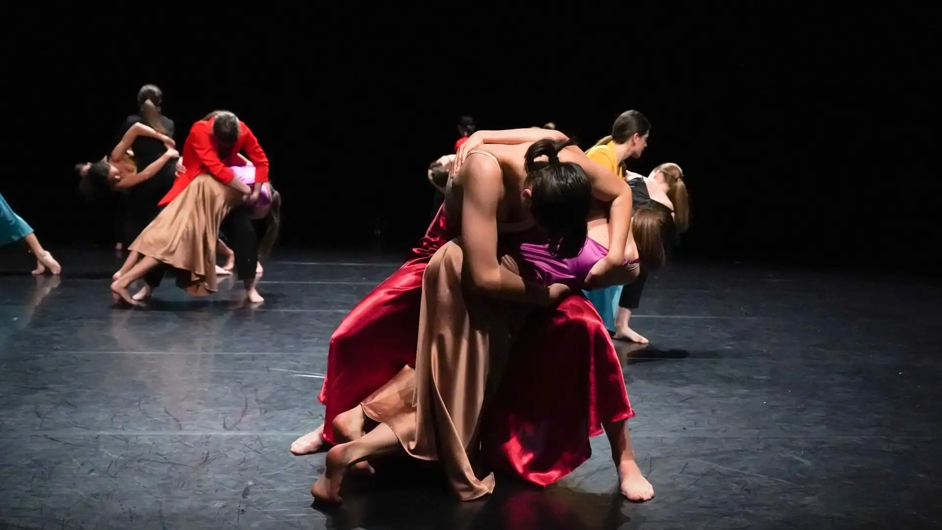 LIEU-DANSE Groupe de danseurs en pleine chorégraphie contemporaine, exécutant des portés dynamiques sur une scène sombre, illustrant de façon métaphorique la collaboration et la précision nécessaires au développement logiciel métier.