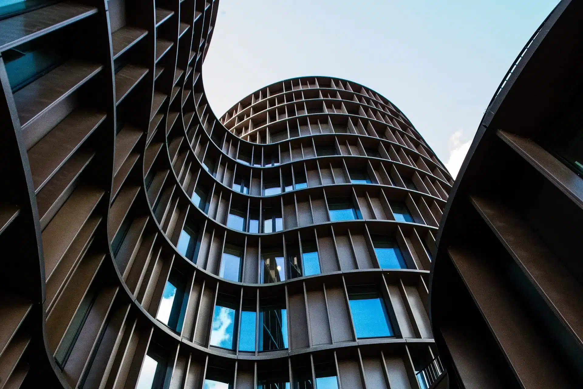 courbes-architecturales Vue ascendante d’un bâtiment aux courbes architecturales modernes, illustrant la réalisation d’une plateforme de gestion d’adhérents développée par Azuracom pour l’UNSFA