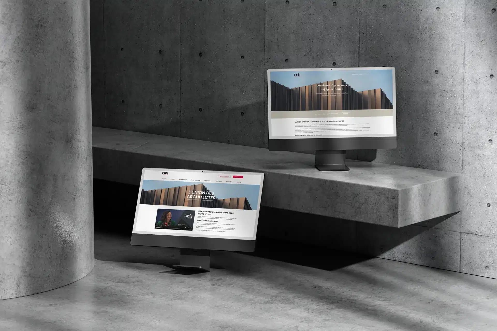 site-UNSFA-deux-ecrans Deux écrans d’ordinateur affichant le site de l’UNSFA sont présentés dans un décor en béton brut, l’un posé au sol et l’autre sur une marche, illustrant une mise en scène moderne ; contenu utilisé dans un contexte lié à la création de plateforme de gestion d’adhérents