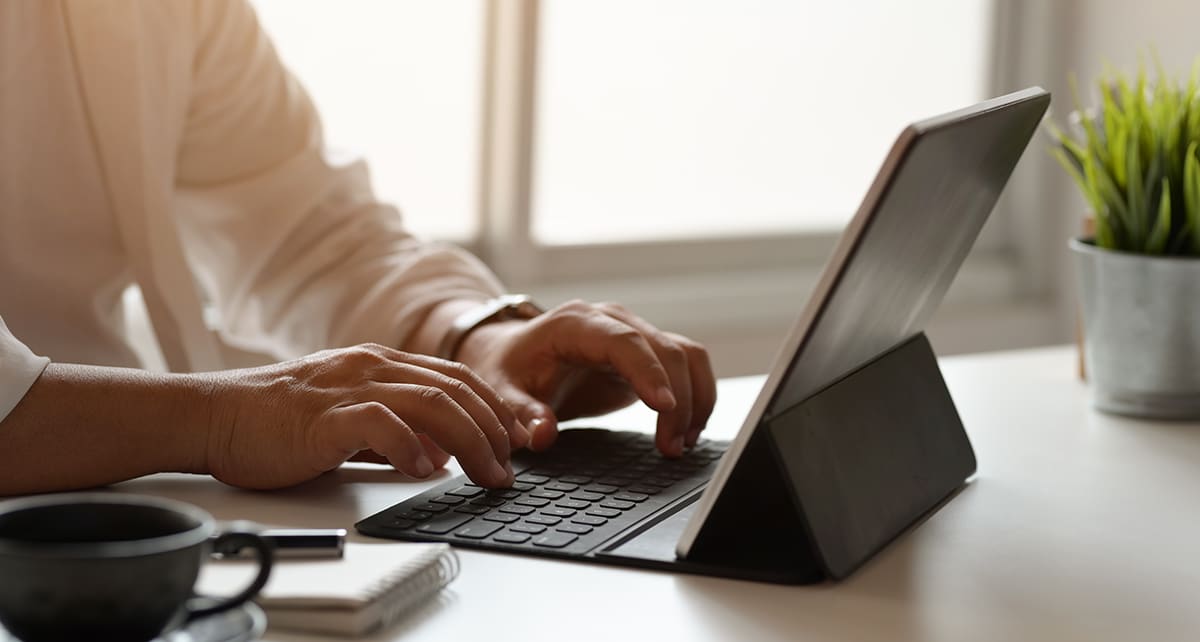 Professionnel travaillant sur une tablette avec clavier dans un espace de travail moderne, illustrant les services d’un intégrateur web à Avignon pour la création et l’optimisation de sites internet.